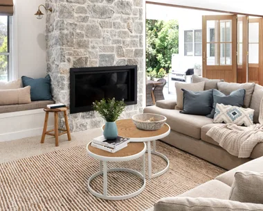 A modern farmhouse living room with a stone fireplace and chunky knitted throw on a lounge.
