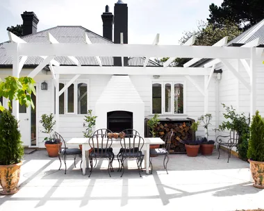 A classic white alfresco area with a stacked outdoor fireplace.