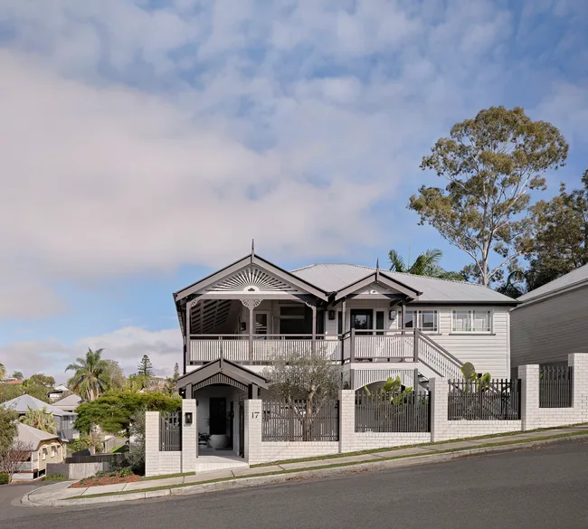An exterior shot of a Queenslander style home, with trims, sills, gutters, fascias, posts and heritage mouldings, as well as weatherboard exterior.