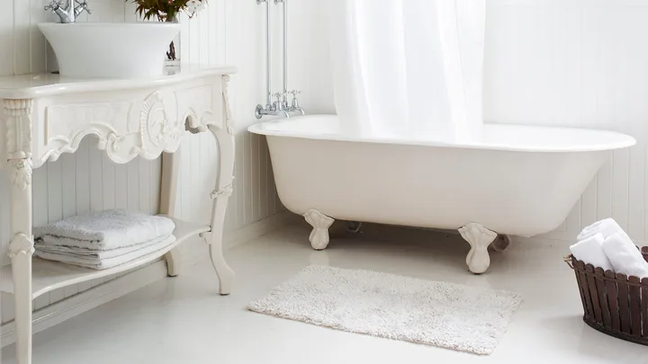 All white bathroom in a cottage with a claw foot cast iron tub.