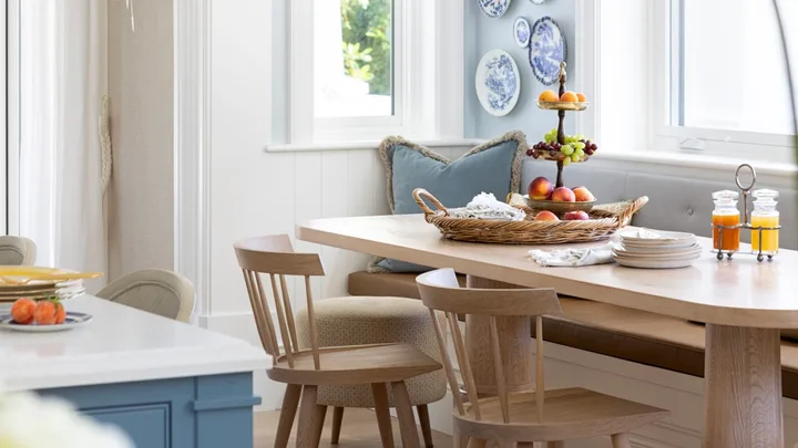 A timber breakfast nook below a wall gallery of decorative plates.