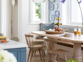 A timber breakfast nook below a wall gallery of decorative plates.