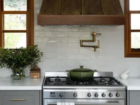 green cast iron pot on stove top with brass pot filler