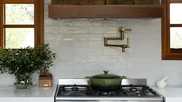 green cast iron pot on stove top with brass pot filler