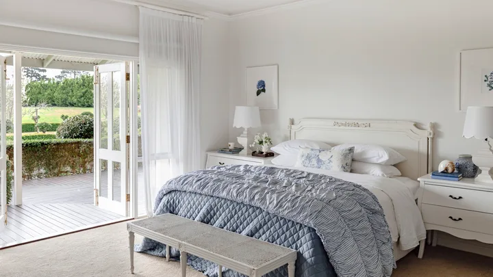 The main bedroom with French doors and classic white and blue furniture.