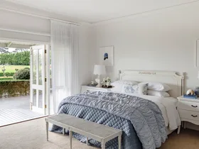 The main bedroom with French doors and classic white and blue furniture.