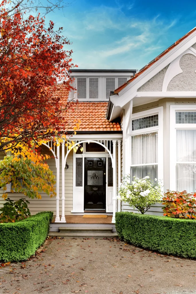 A heritage home exterior with decorative fretwork, leadlight windows and autumn trees.