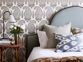 Main bedroom with upholstered pale blue bedhead and paisley wallpaper