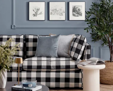 Black and white chequered couch in front of a blue wall with black and white artworks arranged in a grid pattern
