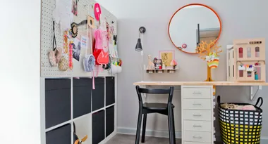 A creative kids' workspace with a desk, chair, colorful decor, wall pegboard, and a mirror on the right.