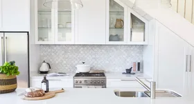 Modern kitchen with white cabinets, marble backsplash, stainless steel appliances, and a bread loaf on a wooden board.