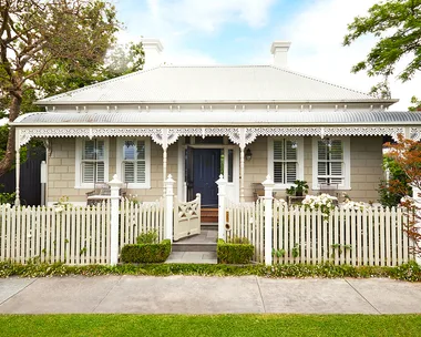 A heritage home with a white facade and picket fence.