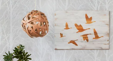 Wooden pendant light and flying birds artwork on tree-patterned wallpaper background.