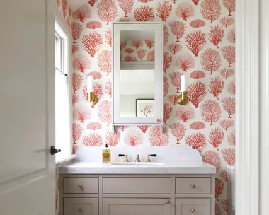 An ensuite with red tree-themed wallpaper and a marble-topped vanity.