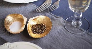 Golden oyster shells used as salt and pepper holders on a table setting.