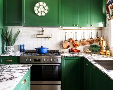 A cottage-style kitchen with green cupboards and a marble island.