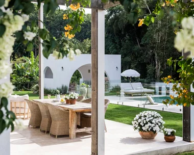 An alfresco dining area with yellow bougainvillea flowering on the pergola above it