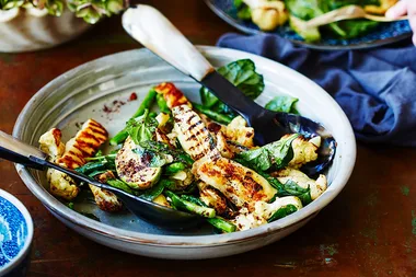 Grilled halloumi salad with spinach, cauliflower, and green beans in a gray bowl with serving tongs on the side.