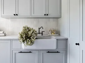 A classic grey country laundry with a farmhouse sink and shaker cabinets.