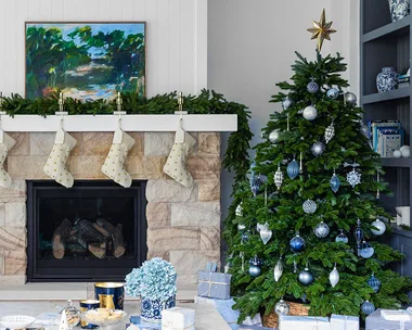 Coastal Christmas living room with blue and silver Christmas tree and sandstone fireplace