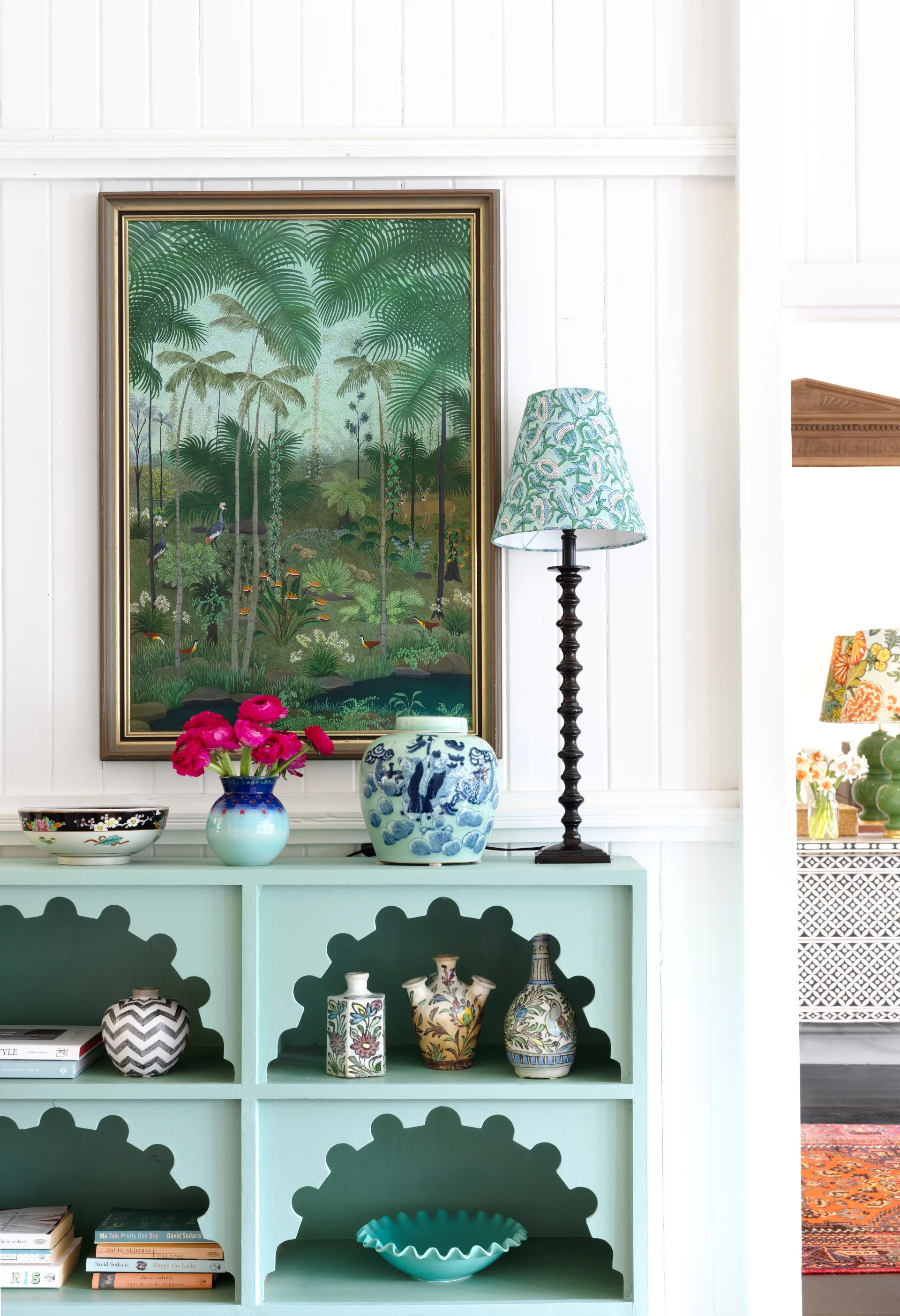 A blue antique Moroccan shelf with a tropical artwork hanging above.