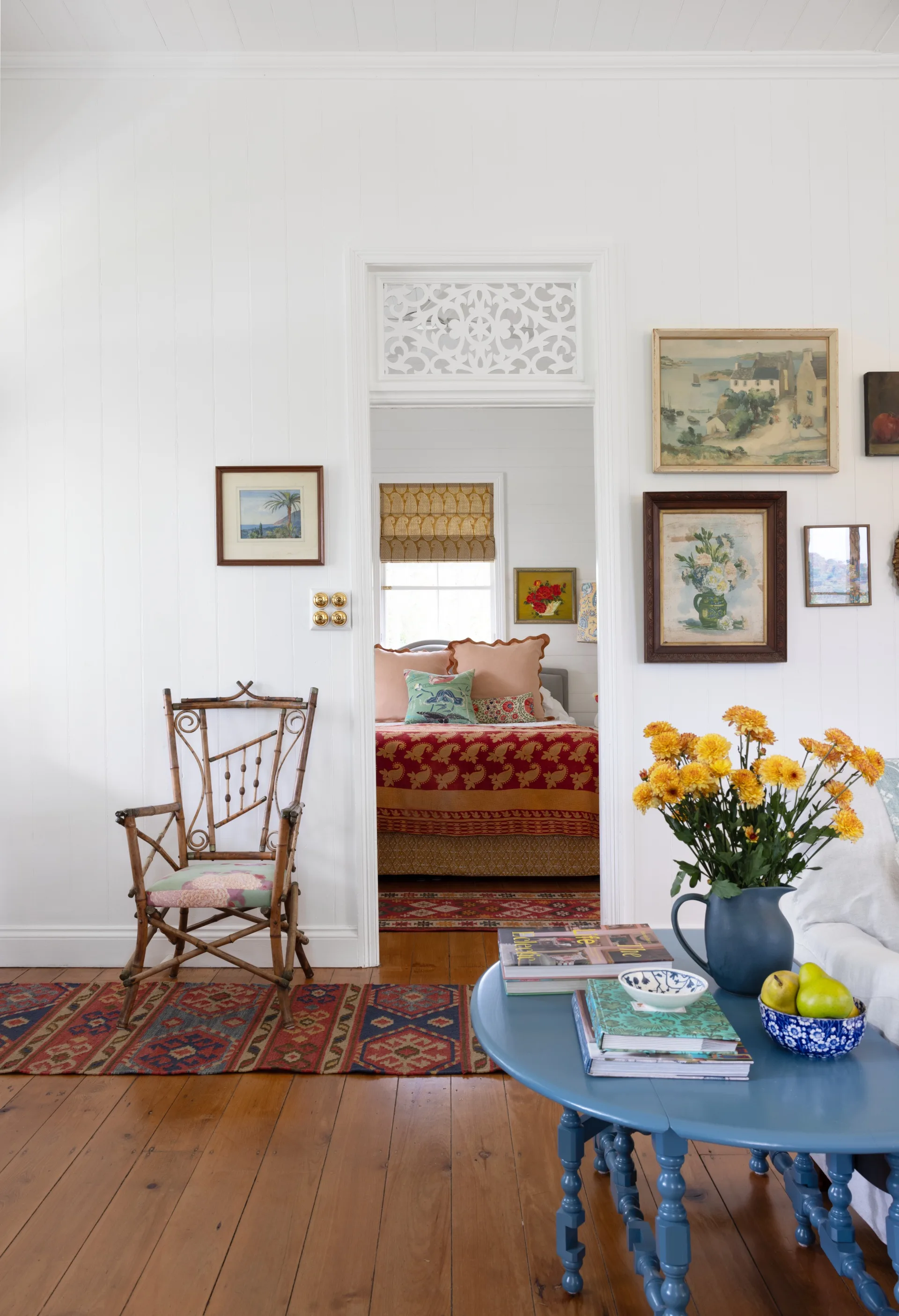 A white living area with blue and timber furniture and a gallery wall.