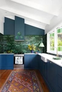 A blue and green modern country kitchen with a subway tile splashback.