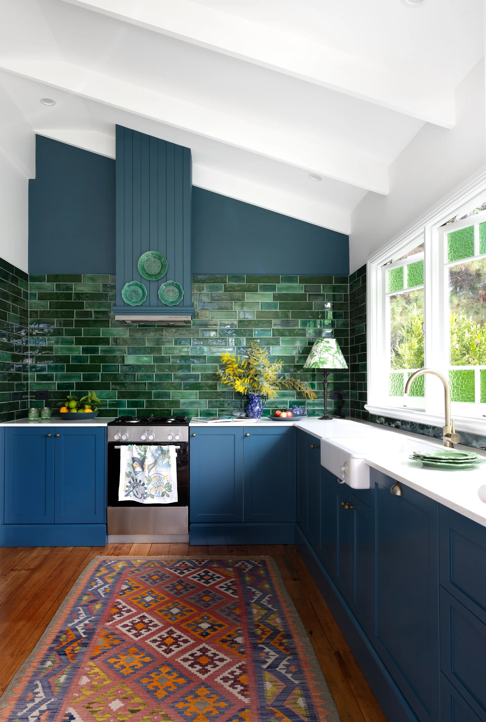 A blue and green modern country kitchen with a subway tile splashback.