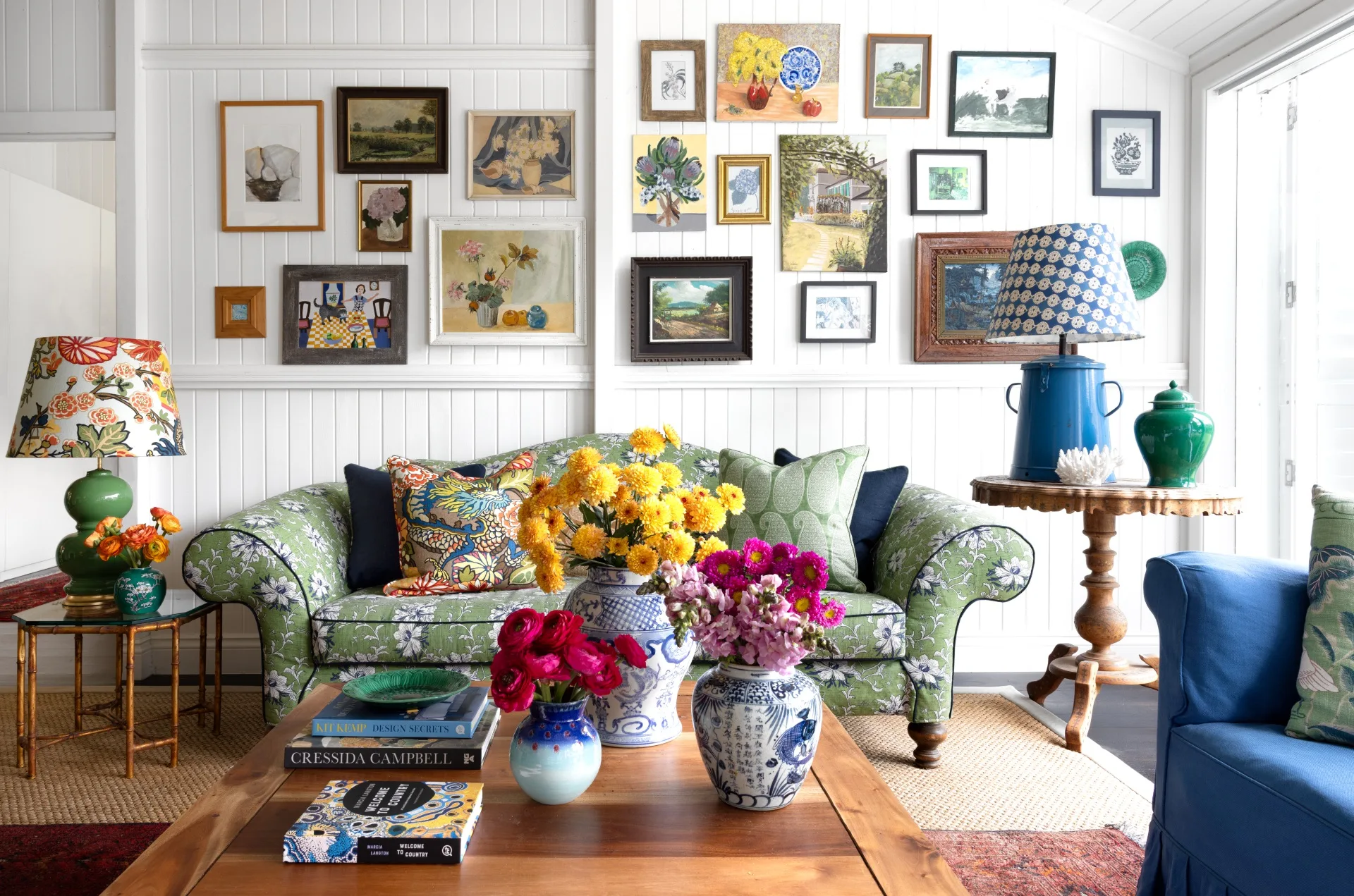 A vintage-style living area with a green sofa and gallery wall.