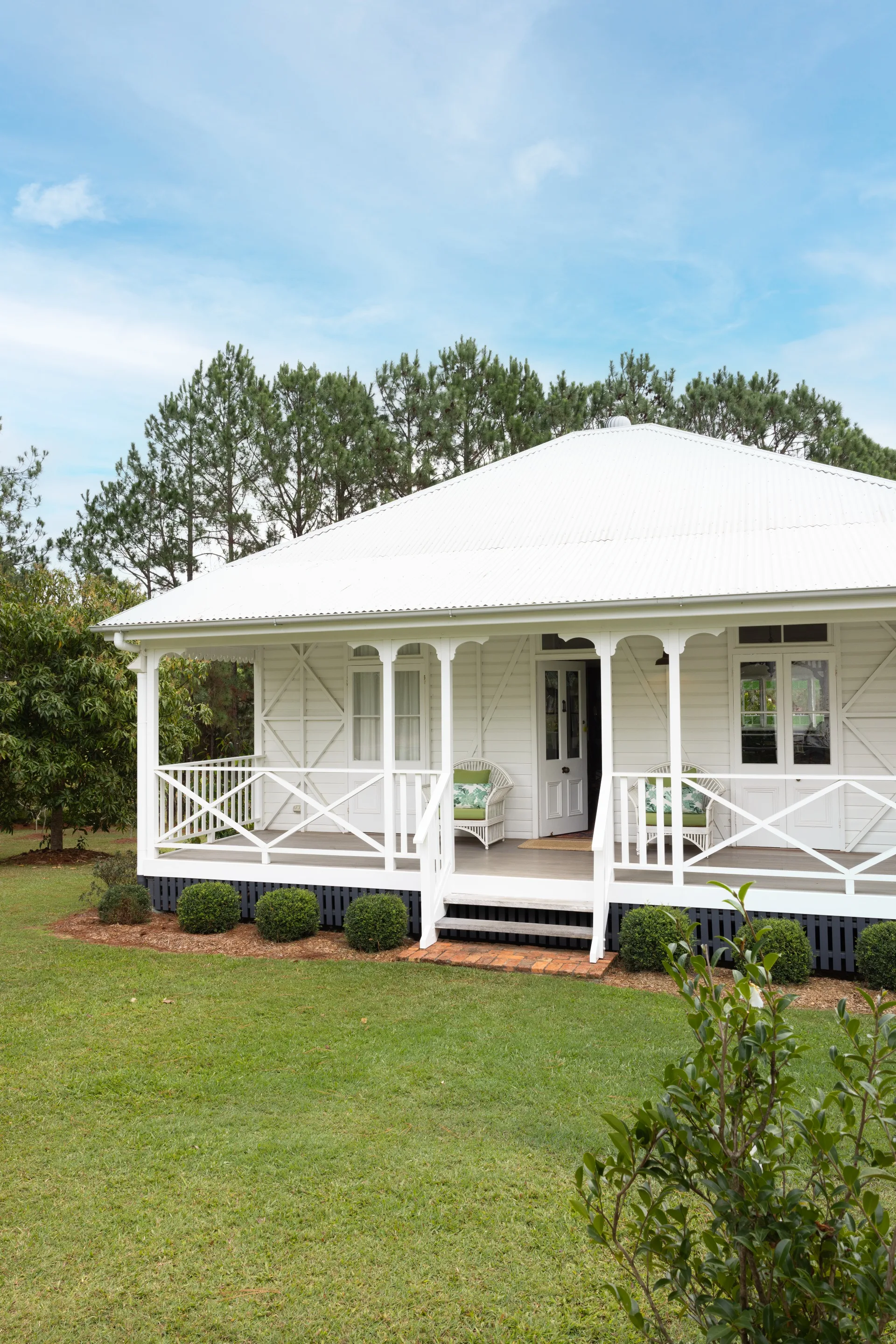 A quaint white farmhouse cottage with a front veranda.