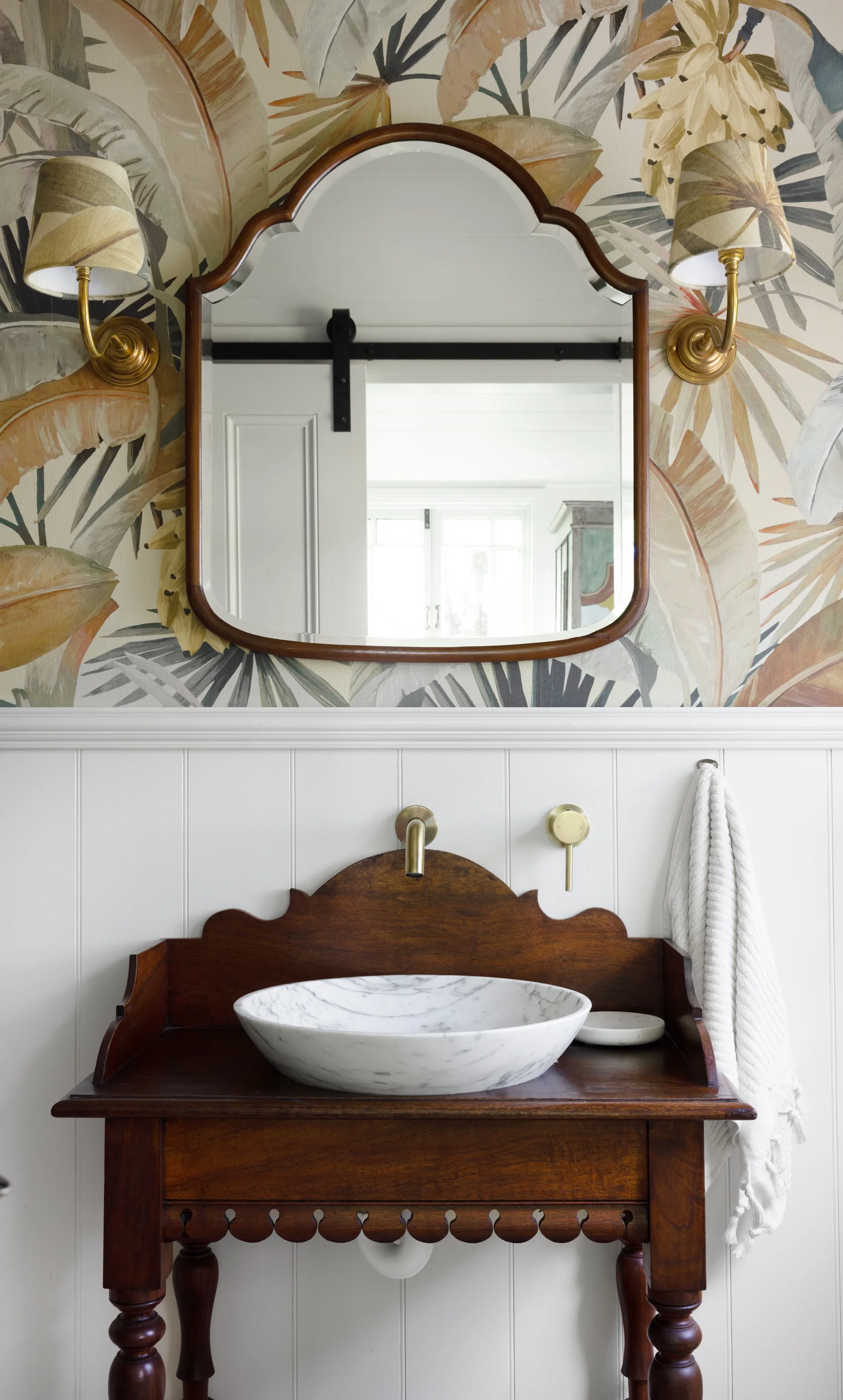 The ensuite with a timber vintage vanity and palm tree wallpaper.