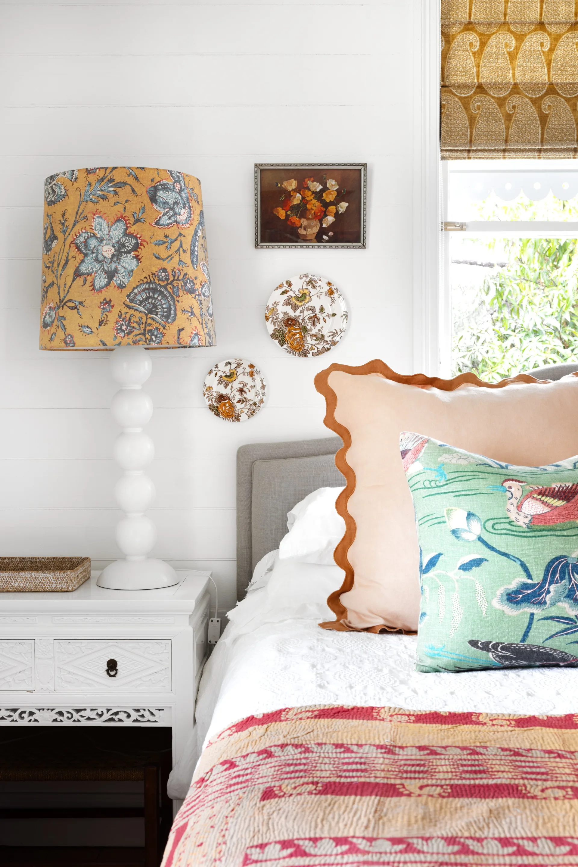 The main bedroom with scalloped pillows and a vintage red and orange bed quilt.