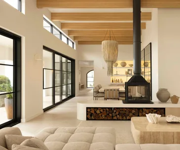 Living and dining room of Sydney coastal house with a Mediterranean aesthetic, featuring a wood fireplace.