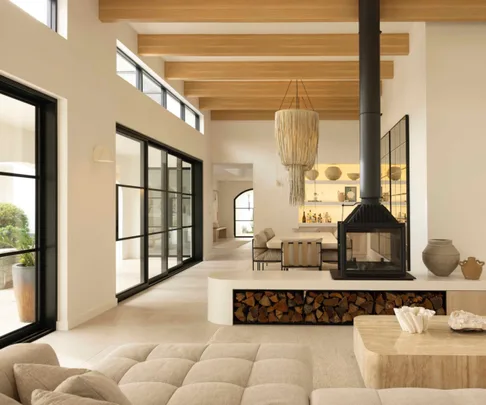 Living and dining room of Sydney coastal house with a Mediterranean aesthetic, featuring a wood fireplace.