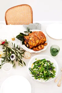 Rolled pork loin with apple and thyme and a bean salad on a white Christmas tablescape.