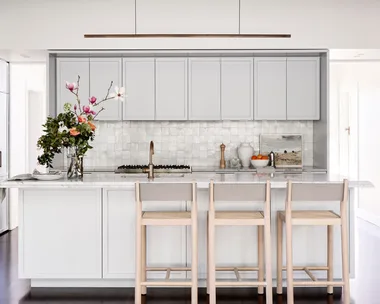 Kitchen with grey cabinetry and a vase of flowers on the island.