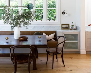 Dark brown leather banquette seating with a large dining table and dining chairs against a white wall