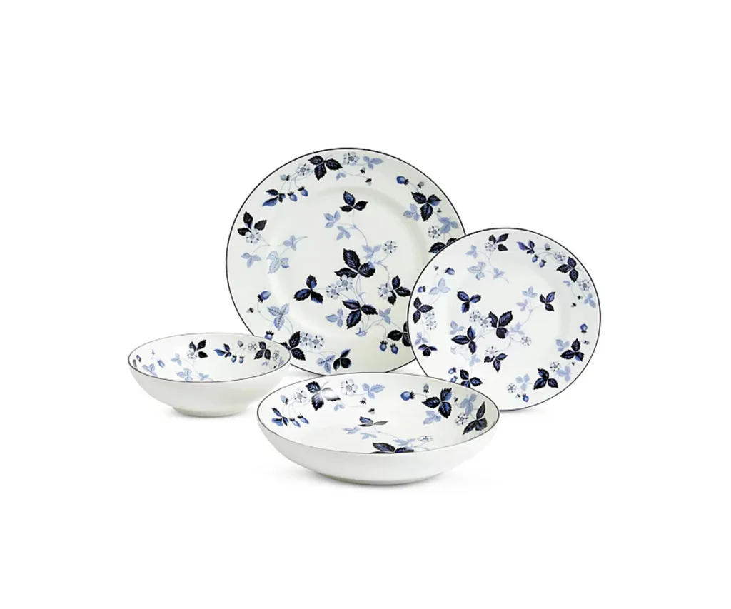 Product shot of the Wedgwood Wild Strawberry Inky Blue Dinnerware Set, ranked our best high end dinnerware set. The set features white plates and bowls with ornate blue patterns depicting strawberries and foliage